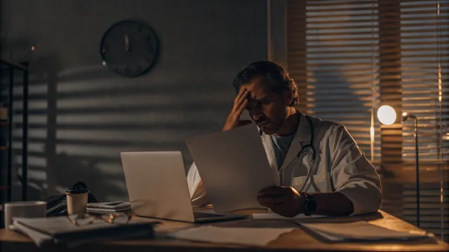 Pessoa digitando em laptop com relogio de areia ao fundo, representando economia de tempo na escrita com IA