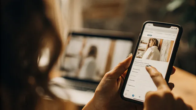 Pessoa com dor nas costas usando smartphone para procurar clínica de fisioterapia